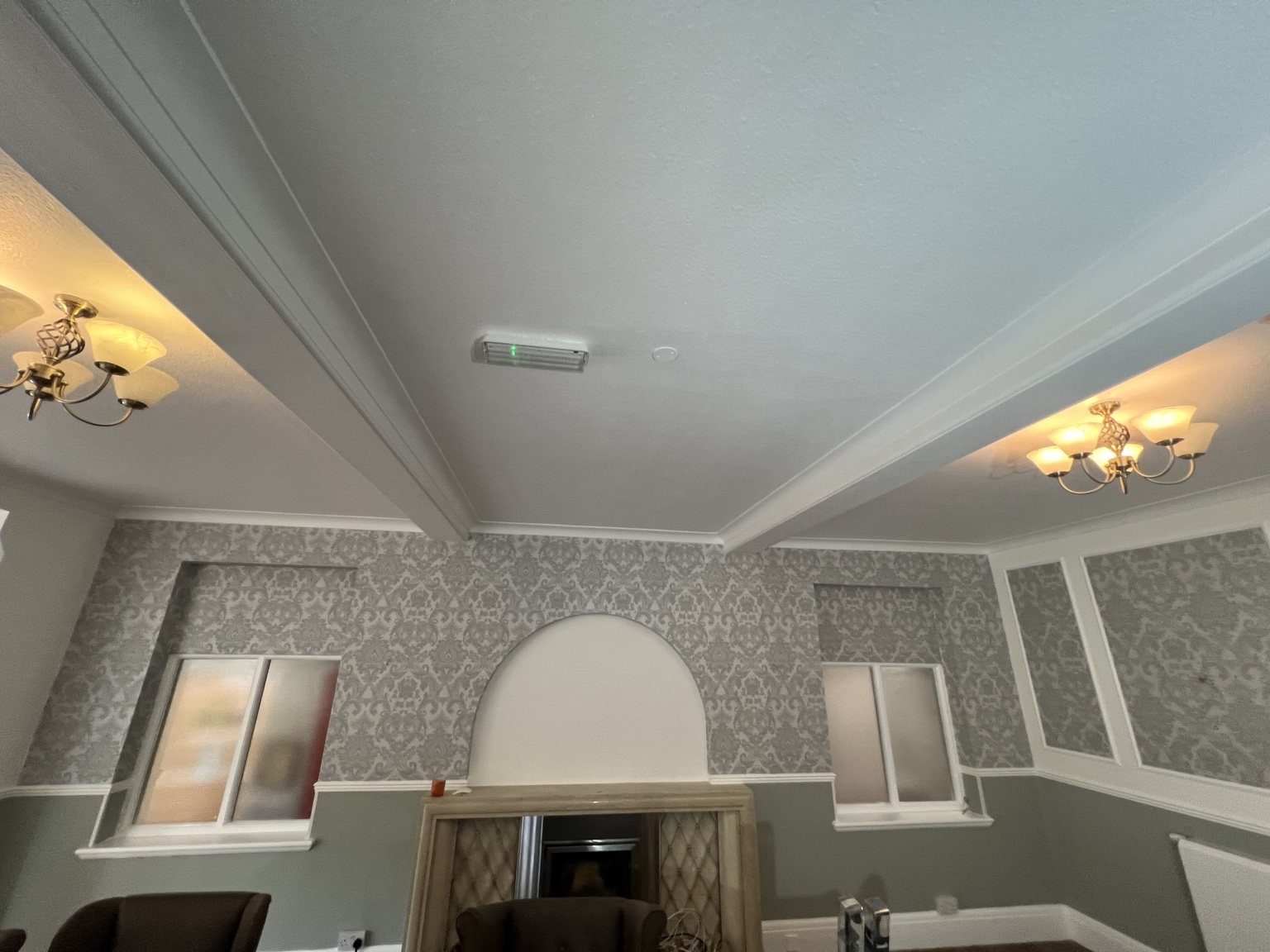 Care home lounge with patterned wallpaper, grey lower walls and white ceiling details