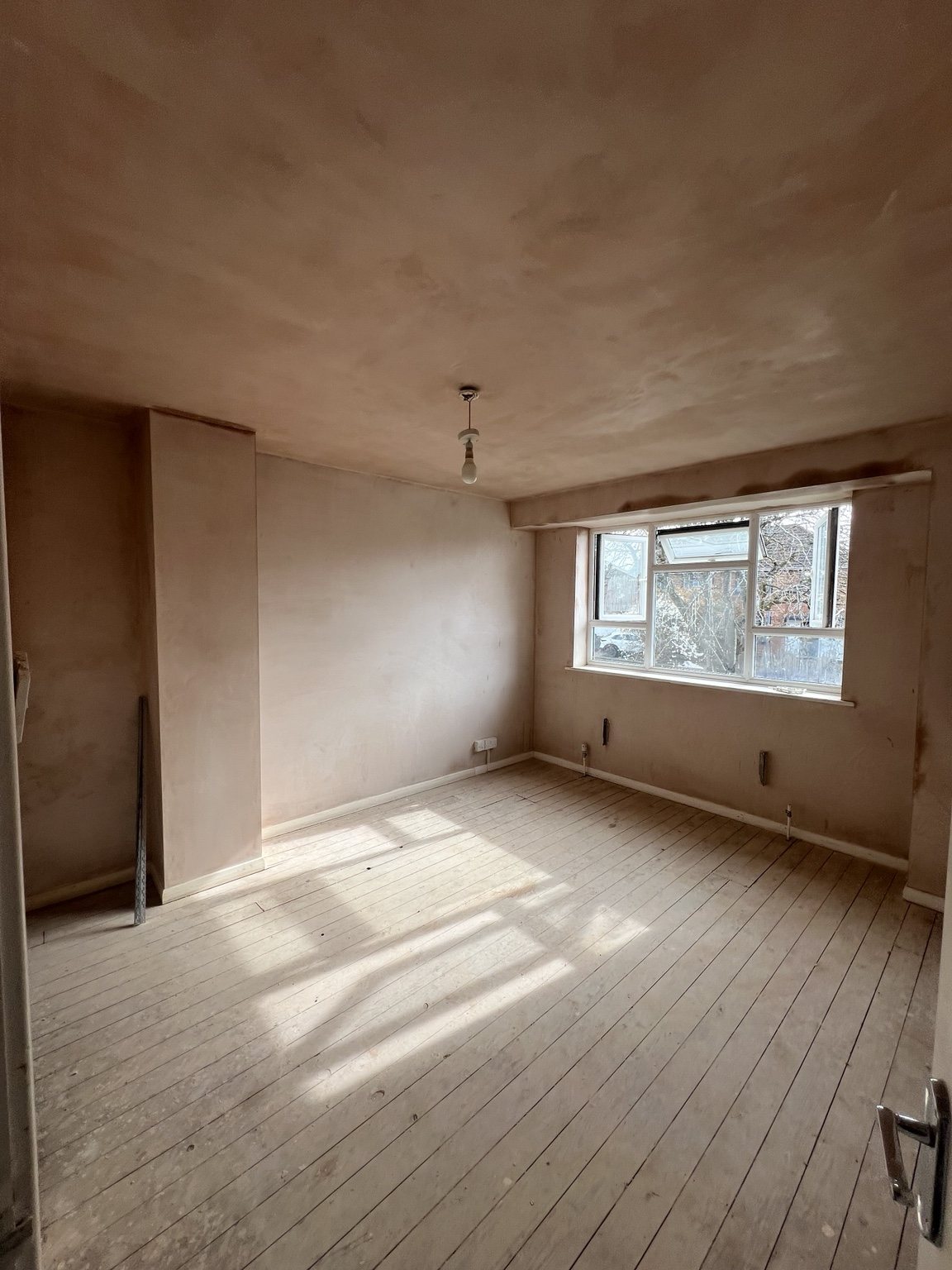 Room in progress with freshly plastered ceiling and walls and exposed floorboards
