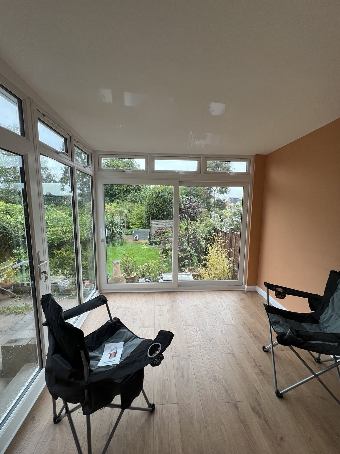 Glazed conservatory with wood-effect flooring and warm painted walls