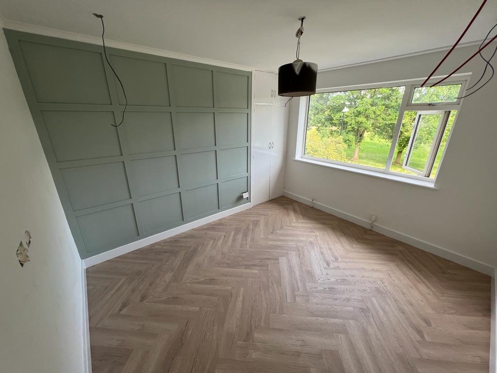 Sage wall panelling and parquet flooring during a room refurbishment