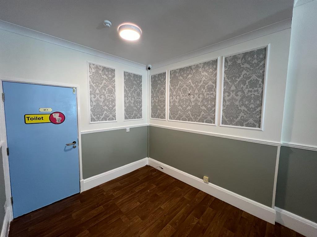 Communal interior with patterned wallpaper, white trim and grey lower walls